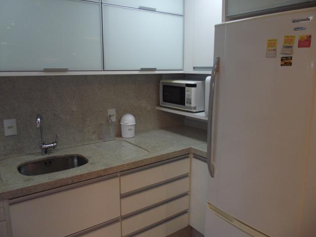 Cozinha com armários planejados, fogão, microondas, geladeira e depurador de água.