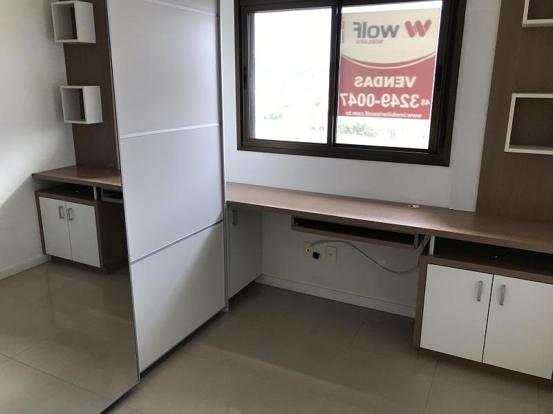 Quarto de solteiro com armários e bancada de estudos.