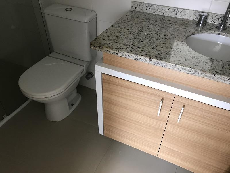 Banheiro Suíte com armários, espelho e box em vidro.